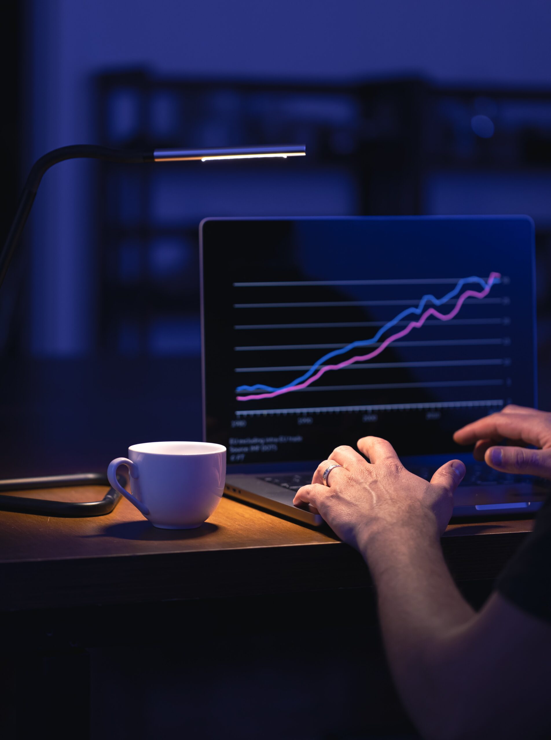 Broker looking at laptop analyzing stock market invest trading stocks graph.